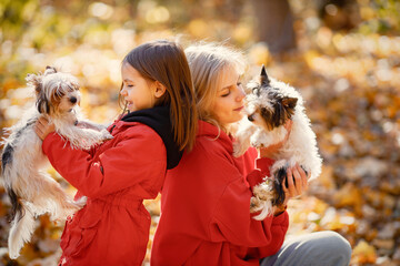 Mother and daughter sitting on a blanket in autumn forest with dogs