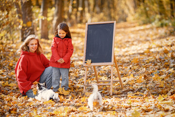 Mother and daughter playing in autumn forest with dogs