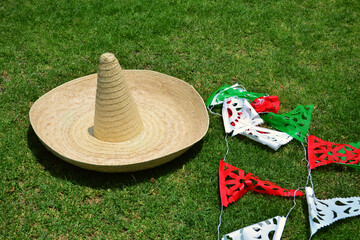 15 of September. Traditional Mexican hat on the grass, and traditional decorative paper of patriot...