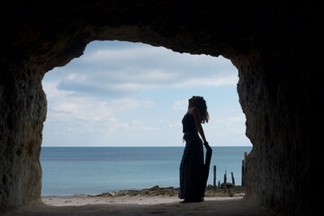 Woman in cave as silhoutte with beautiful ocean in the background