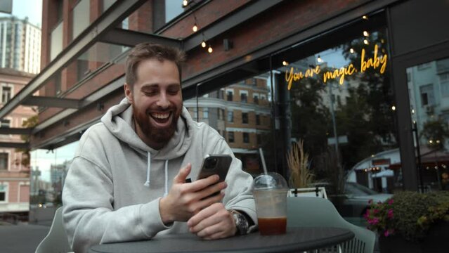 Attractive young man with a beard scrolls social networks on his phone and drinks coffee on a date with a woman.