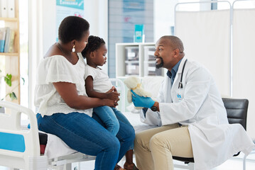 Doctor or pediatrician gives a teddy bear to a little girl after a medical appointment in a clinic...