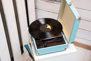 Analog vinyl record player with disc on white table. Modern turntable audio equipment.