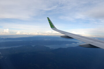 Airplane wings flying in the air with shining sky