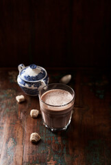 Glass of chocolate milkshake on dark wooden background.	