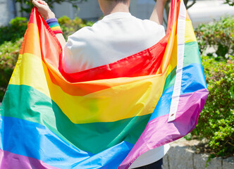 LGBTQイメージ　外で虹色のマントを羽織る男性の後ろ姿