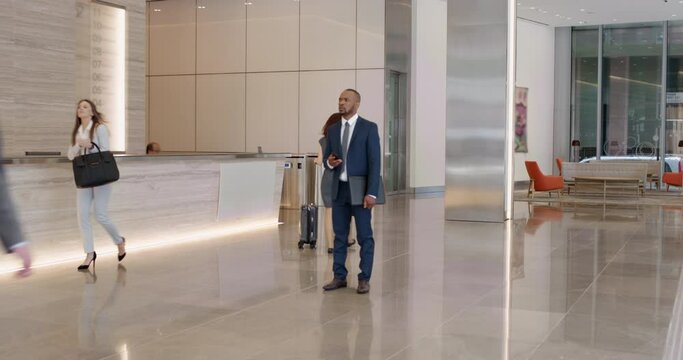 Confused business man texting on phone in office building, unsure of the message he read. Serious male corporate employee concerned with fake news or online scam, checking internet and social media