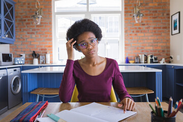 Portrait of tensed african american teenage girl studying at home