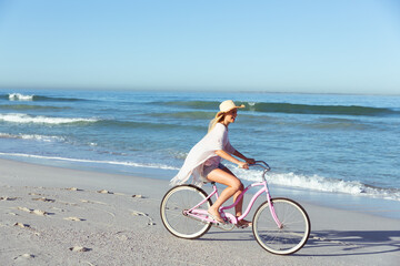 Caucasian woman spending time seaside and riding a bike
