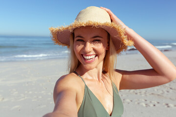 Caucasian woman using a phone and taking selfie at beach