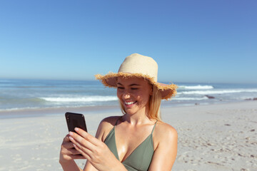 Fototapeta premium Caucasian woman using a phone and taking selfie at beach
