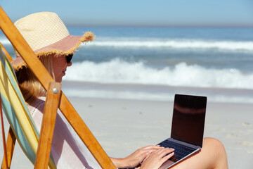 Caucasian woman using her laptop seaside
