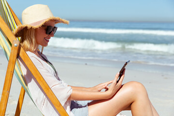 Caucasian woman using a digital tablet seaside