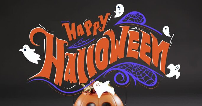 Animation of happy halloween text with ghosts over orange pumpkin bucket with sweets