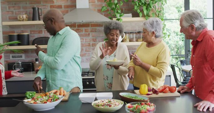 Group of happy diverse senior friends cooking together in kitchen