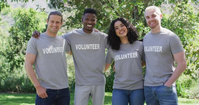 Portrait of smiling, diverse group of happy friends in volunteer t shirts embracing outdoors