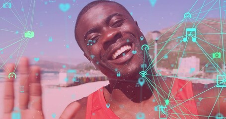 Globes of digital icons spinning against african american fit man waving looking at the camera