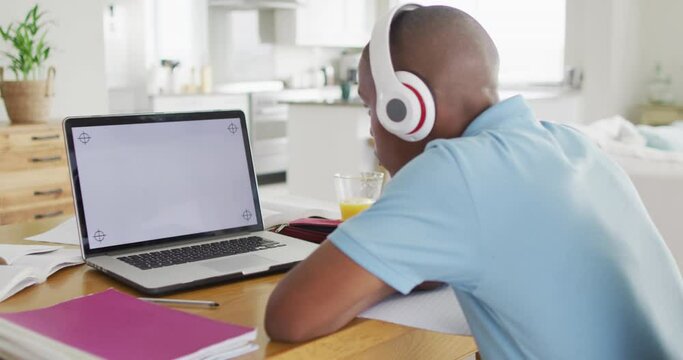 Video of focused african american boy with laptop with copy space having online lessons at home