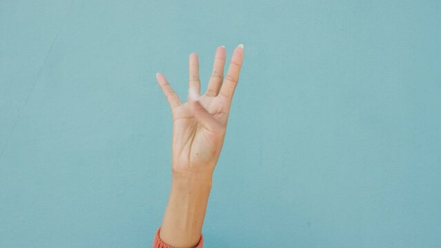 Countdown fingers or hand gesture on a mockup blue wall background. Woman hands counting one, two, three and four, five numbers for a sale, discount or competition with advertising, marketing mock up