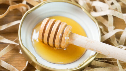 Honey dipper surrounded by honey on wood background. Health and beauty product sustainable...
