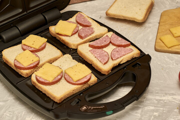 sandwich maker cheese sausage and bread on the table