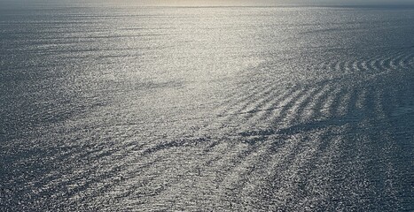 Sea water silver shiny glittering surface at evening. Romantic rippled seascape.