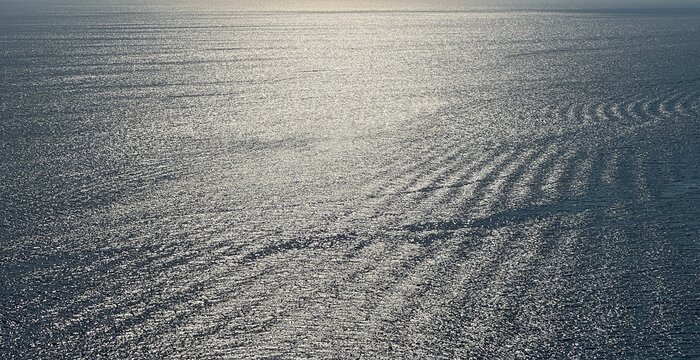 Sea water silver shiny glittering surface at evening. Romantic rippled seascape.