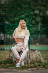 Obraz premium Portrait of a young beautiful girl in a city park in a sports suit.