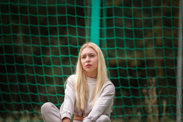 Portrait of a young beautiful girl in a city park in a sports suit.