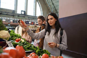 Shot of two young couples choosing and buying vegetables in modern vegetable shop in marketplace.