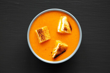 Homemade Tomato Soup with Grilled Cheese Croutons on a black background, top view. Flat lay, overhead, from above.
