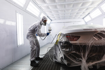 Mixed race car painter painting a car