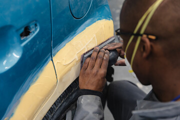 African American mechanic man sanding a car