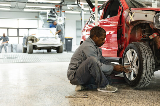 African American mechanic working on a car wheel