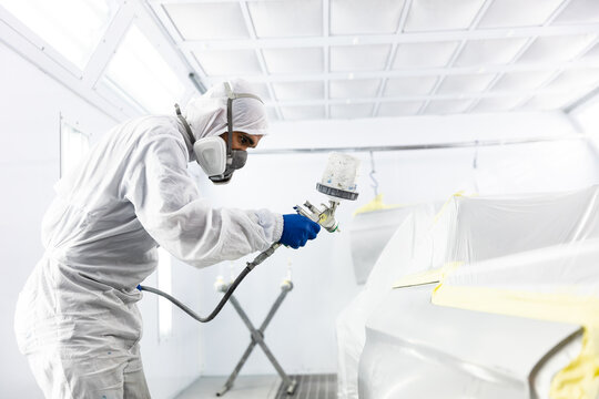 Mixed race car painter painting a car