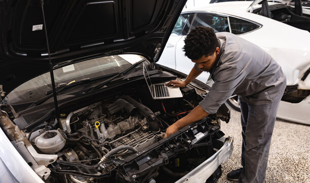 Mixed race mechanic man inspecting car motor