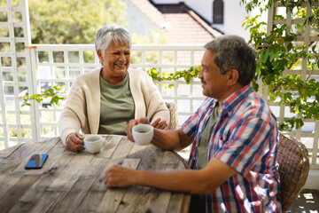 Senior african american couple sitting by table drinking coffee on terrace