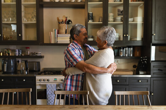 Senior african american couple standing and hugging in a kitchen