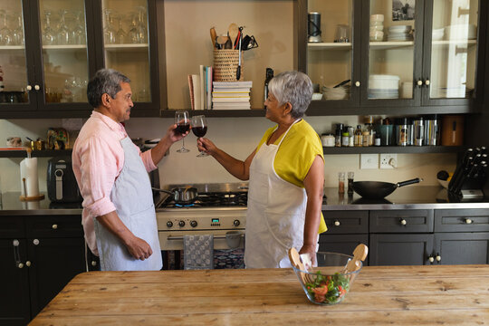 Senior african american couple drinking wine making a toast in kitchen