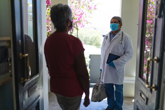 Senior african american male doctor and woman wearing mask saying goodbye