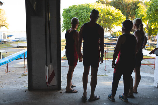 Rear view of senior caucasian rowing team standing together in the boat warehouse