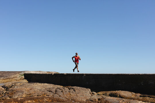 Fit senior african american man exercising running on coastal path