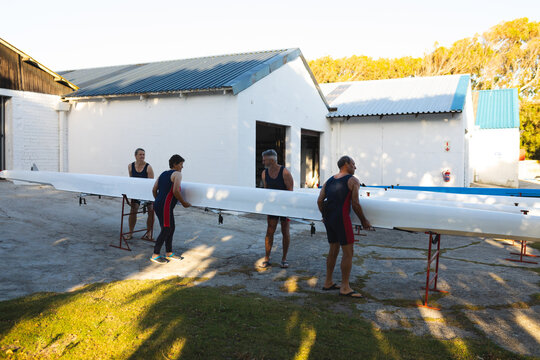 Senior caucasian rowing team carrying boat together to the lake