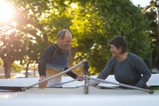 Senior caucasian rowing couple carrying boat together to the lake - Powered by Adobe