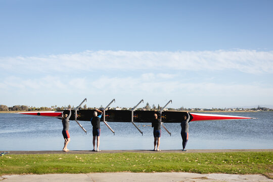 Senior caucasian rowing team putting the boat in the lake while standing on the wooden dock