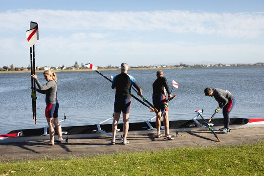 Senior caucasian rowing team attaching oars to the boat near the wooden dock