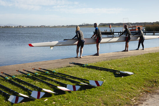 Senior caucasian rowing team putting the boat in the lake while standing on the wooden dock