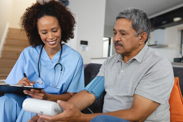 Senior mixed race man with female doctor home visiting taking blood pressure
