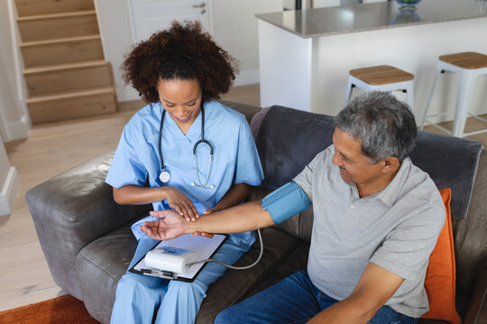Senior mixed race man with female doctor home visiting taking blood pressure