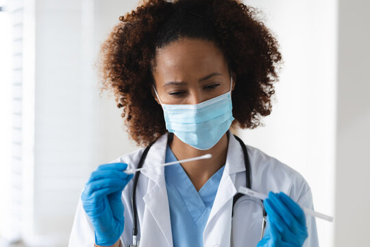 Mixed race female doctor wearing mask inspecting patient swab test